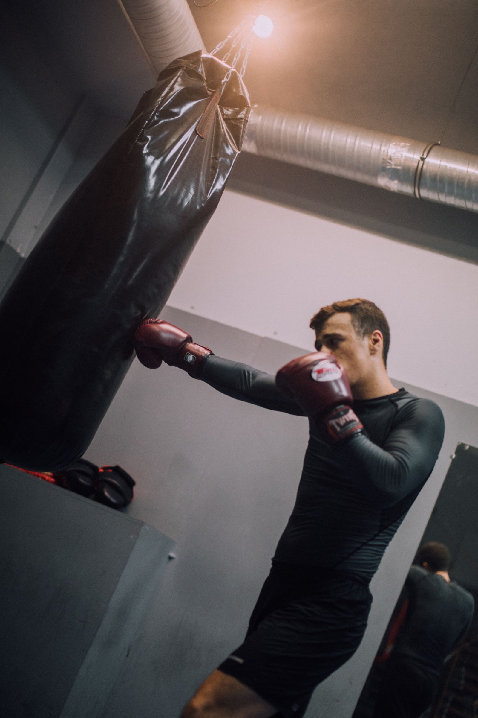 Boxer trainiert mit Boxhandschuhen am Sandsack im Gym