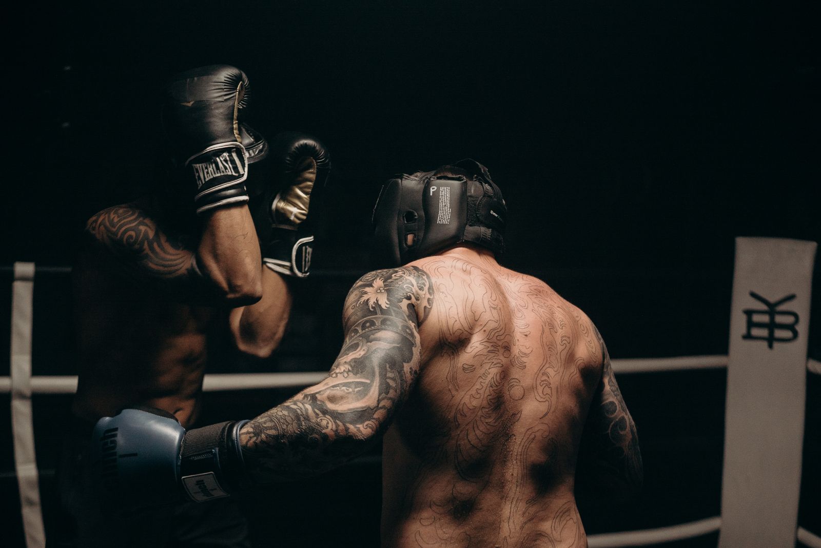 Zwei Boxer beim Sparring im Ring, einer trägt Kopfschutz