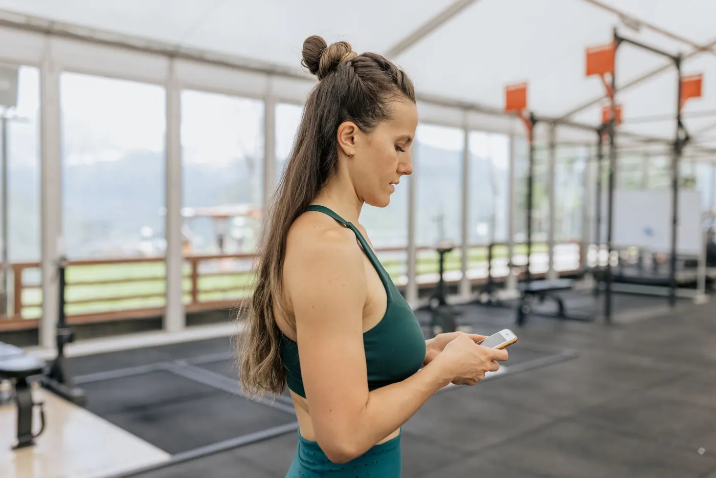 Athletin öffnet auf ihrem Smartphone die App im Trainingsraum